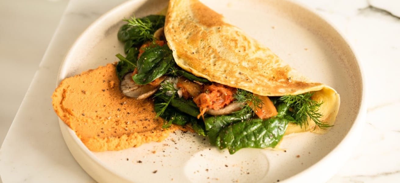 A savoury omelette served on a plate, enfolding a variety of vibrant, colorful vegetables.